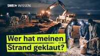 Bauarbeiten am Strand bei Nacht: Arbeiter mit Sandsäcken, Kran und Holders.